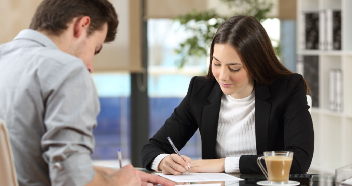 A business owner reviews a document with a client. A business owner reviews a document with a client.