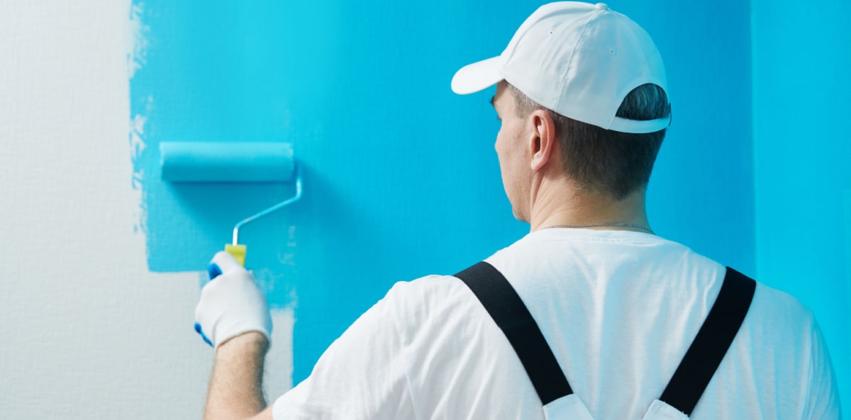 Painting contractor applying a coat of paint to the walls of a commercial building.