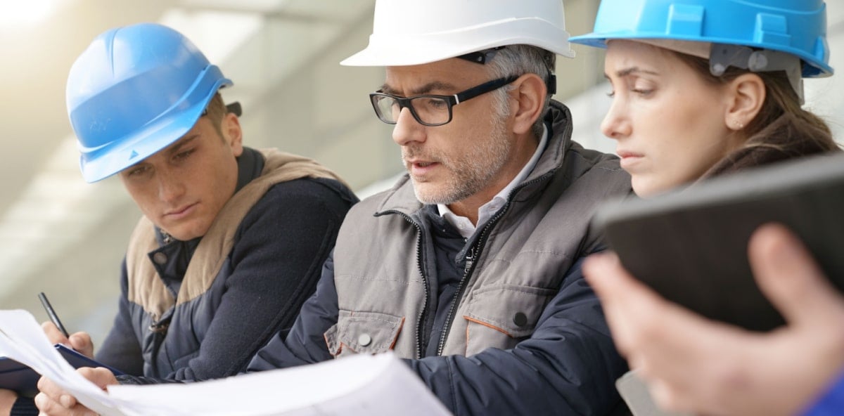 Architects and engineers closely examining a project plan. Architects and engineers closely examining a project plan.