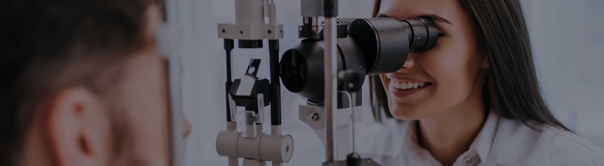 Female doctor ophthalmologist is checking the eye vision of a young man in modern clinic.