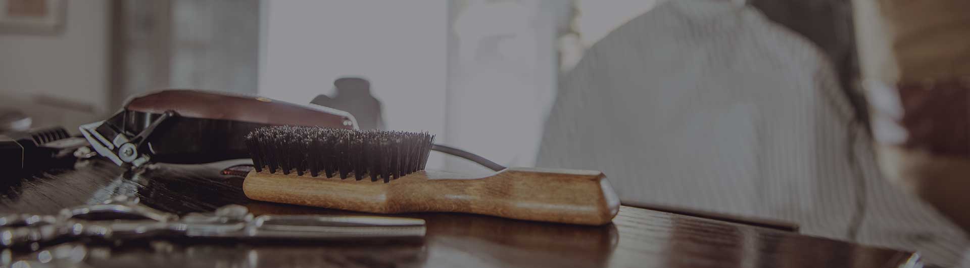 Barbershop tools including a brush, scissors, and a comb on a table.