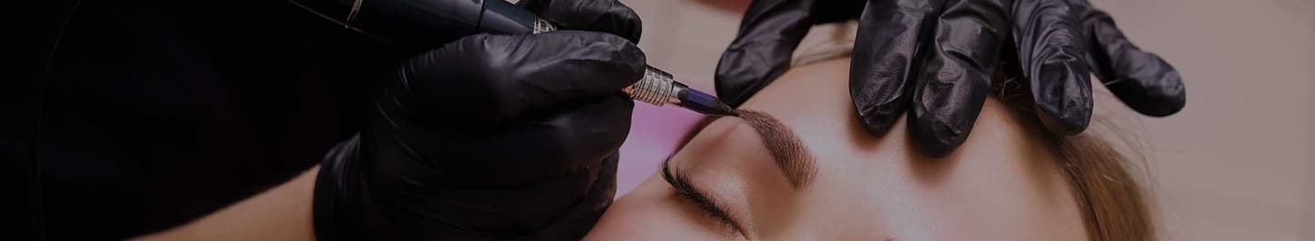 Permanent makeup artist working on a female client's eyebrows. Permanent makeup artist working on a female client's eyebrows.