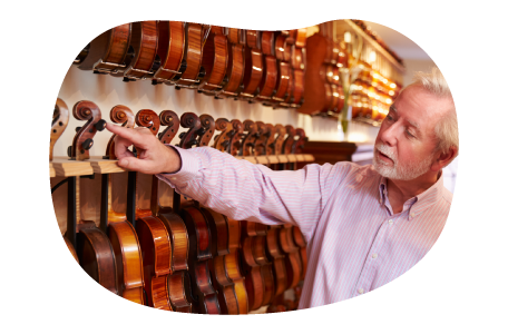 Music store employee scanning through a shelf holding violins.