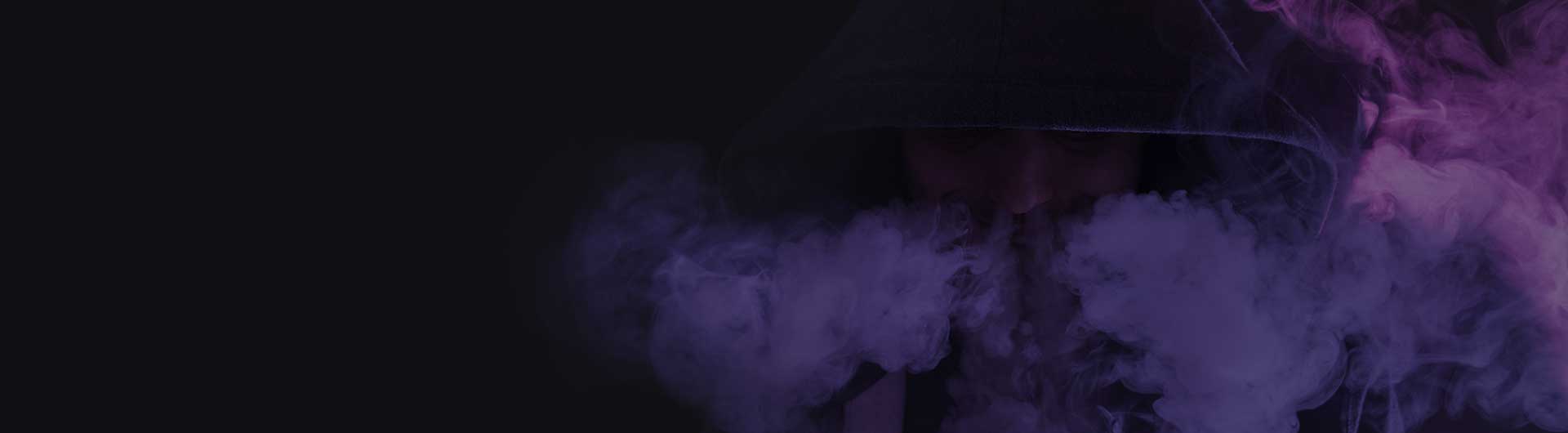 Young man on a dark background holding an electronic cigarette, vaping device.