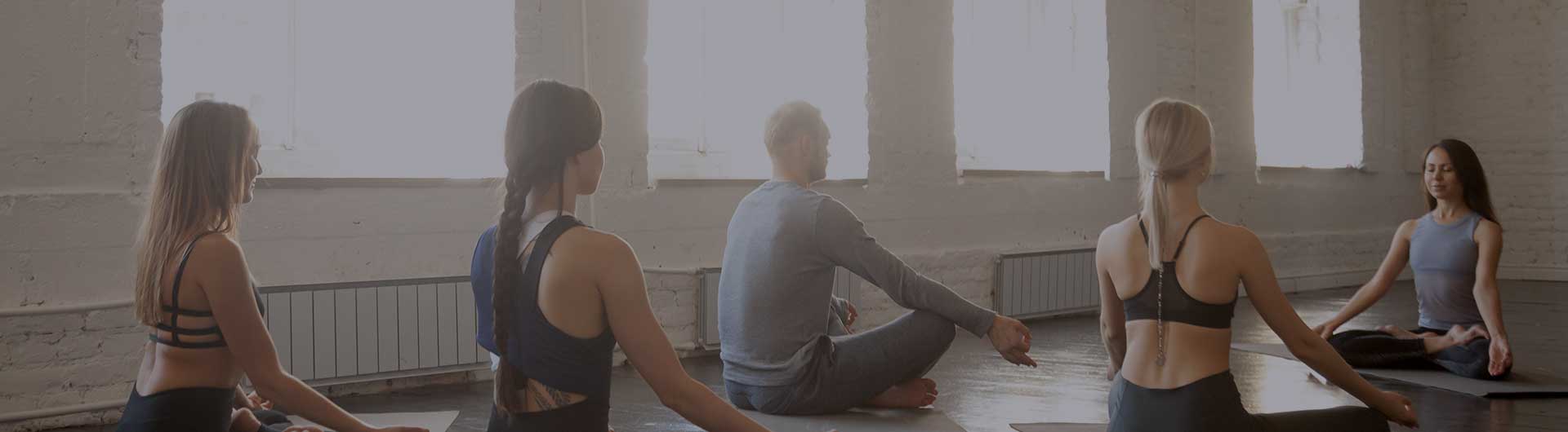 Several people sitting on the floor in a yoga class.