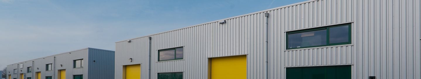 Exterior of commercial warehouses with yellow roller doors.