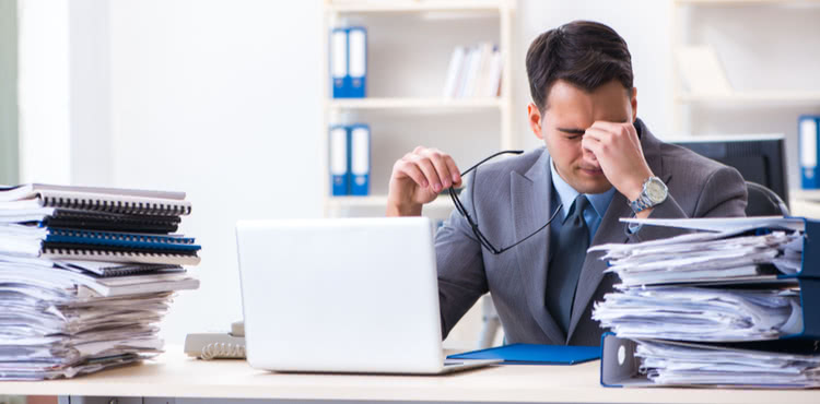 Overworked businessman at desk with paperwork.