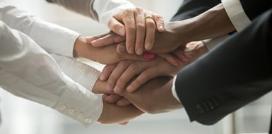 Business owner and employees stacking their hands on top of one another.