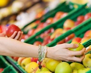 A hand looking through produce at a market.