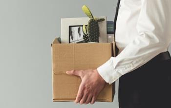 A man carrying a cardboard box of office items.