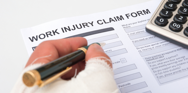 Filing a work injury claim form with bandaged hand.