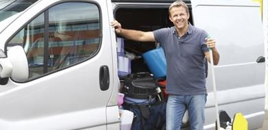 Man stands by a van full of cleaning supplies.