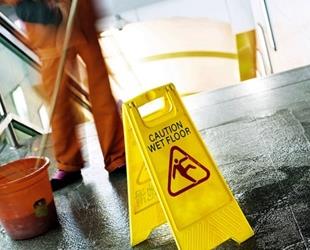 A person mops in front of a caution wet floor sign.