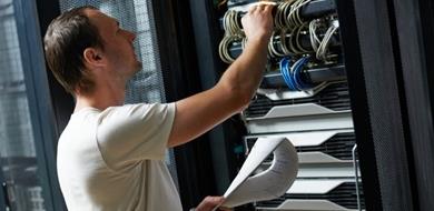 An IT technician completes a checklist in a server room.