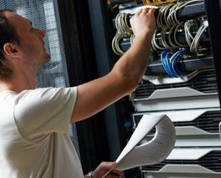 An IT technician completes a checklist in a server room.