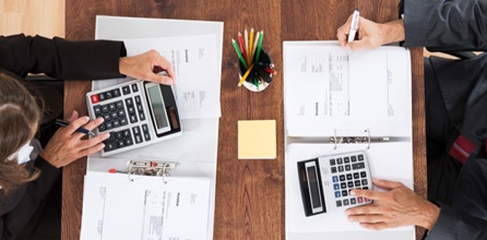 Two accountants calculate budget using calculators.