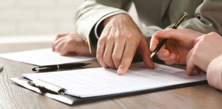 Two people examine and sign a document.
