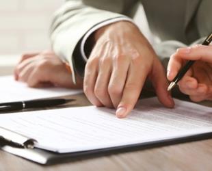 Two people examine and sign a document.