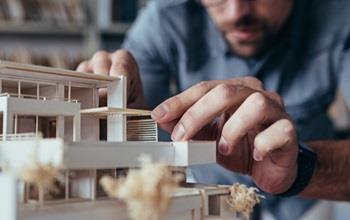 An architect builds a wooden building model.