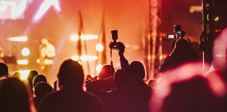 Photographers work in silhouette at a concert.
