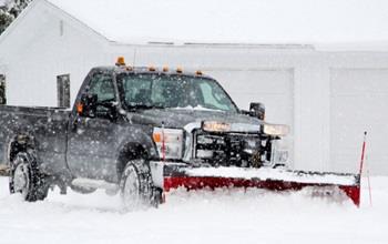 A plow truck clears a driveway in Michigan.