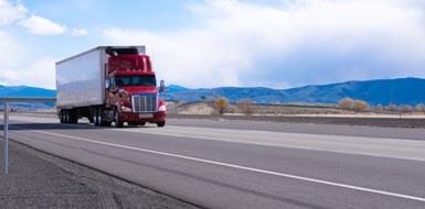 A red semi truck cruises down a highway in Utah.