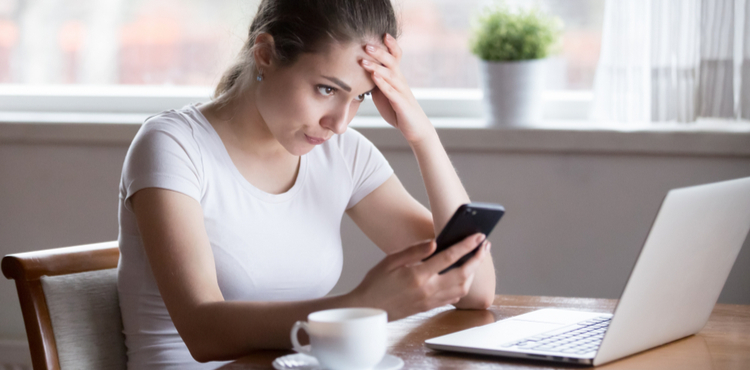 A stressed woman works on a laptop at home.