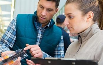 Two people inspect a product in a shop.
