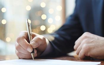 Closeup of a person's hand signing a document.