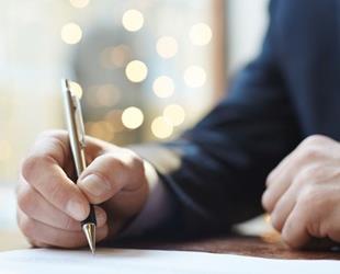 Closeup of a person's hand signing a document.