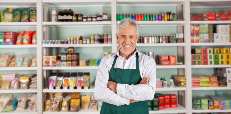 A shopkeeper smiling in front of colorful shelves.