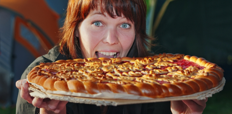 A woman takes a bite out of a pizza pie.
