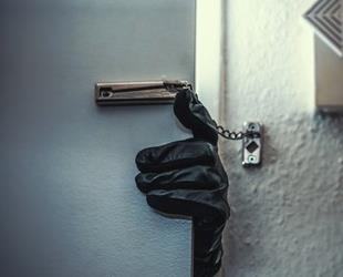 A gloved burglar's hand opening a locked door.