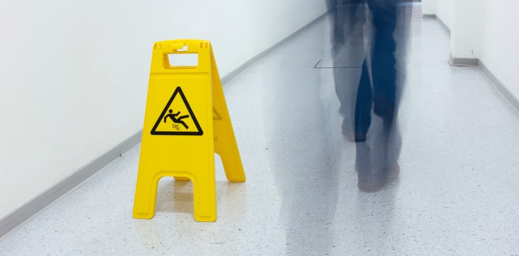 A caution wet floor sign and a man walking by.