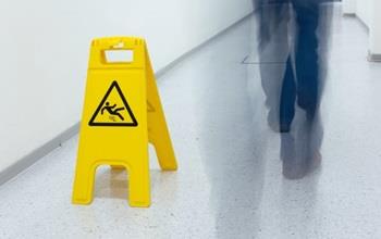 A caution wet floor sign and a man walking by.