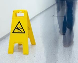 A caution wet floor sign and a man walking by.