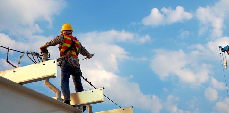 A construction worker standing on a roof. A construction worker standing on a roof.