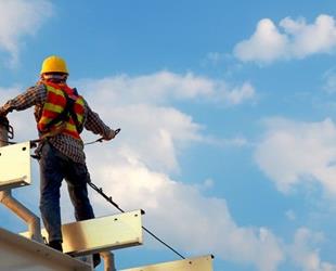 A construction worker standing on a roof.