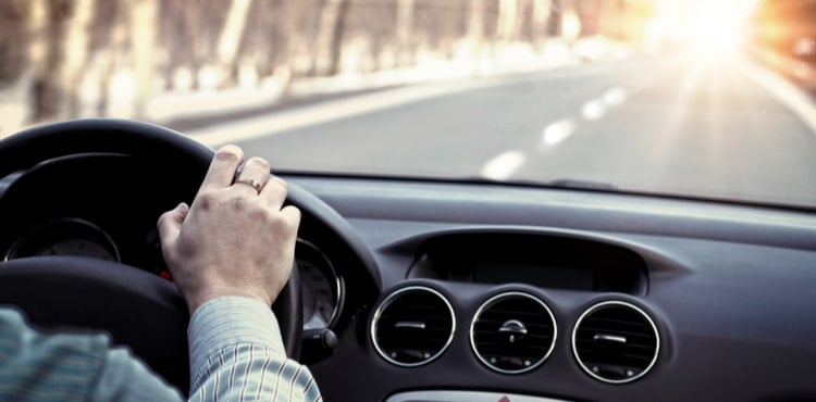 A man's hand on the steering wheel of a car driving down a road. A man's hand on the steering wheel of a car driving down a road.