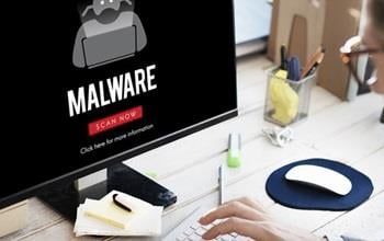 A man looking at a computer screen that says 'malware'.