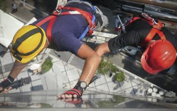 Two construction workers in helmets up high on a building.
