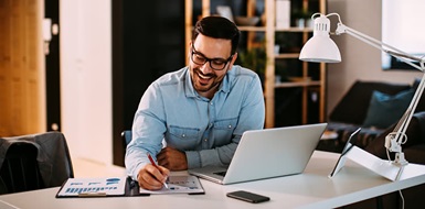 Insurance agent working at home with laptop and papers.