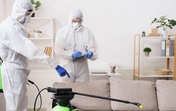 Two cleaners in protective gear using cleaning solution
