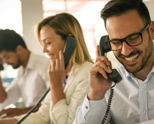 Three cheerful people talking on the phone.