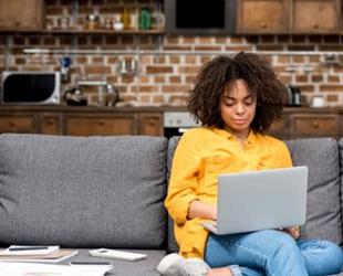 Young woman on couch working on a laptop