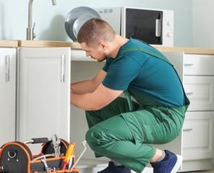 Plumber fixing pipes in kitchen