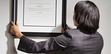 Business consultant hanging framed certificate on office wall.