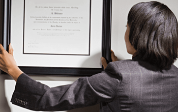 Business consultant hanging framed certificate on office wall.