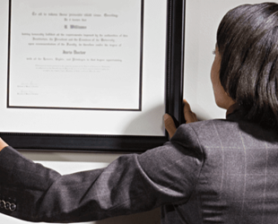 Business consultant hanging framed certificate on office wall.