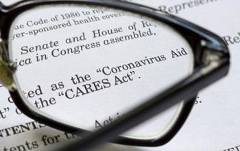 Reading glasses resting on top of a copy of the CARES COVID relief act.